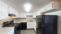 This two-story, 2-bedroom, 1.5-bathroom residence offers a well-organized layout with distinct living areas across both floors. The kitchen is a functional highlight, featuring crisp white cabinetry, a mosaic tile backsplash, light stone-look countertops, dark wood-style flooring, and a full suite of black appliances including a range, dishwasher, and refrigerator. A dedicated dining area with dark hardwood-style flooring and a pendant light fixture provides an ideal space for meals and entertaining.

Both bedrooms are generously sized, finished with neutral carpet and soft, light-toned walls that create a calm and comfortable atmosphere. Each bedroom includes closet space, with at least one featuring a sliding-door closet with a full rod and shelf system. Natural light enters through windows fitted with blinds.

The primary bathroom includes a wide vanity with a speckled countertop, dual sinks, white cabinetry with decorative paneling, and a large mirror with a lighted bar fixture. The full bathroom features a white tub-shower combination with tile surround, complemented by wood-style flooring. A half bath with a single-sink vanity and speckled countertop completes the layout. Throughout, the home maintains a clean, neutral palette with textured ceilings and consistent finishes.