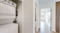 Located at 3046 Merchant Way in Langford, BC, this thoughtfully designed 2-bedroom, 2-bathroom unit offers a clean, modern aesthetic throughout. Light wood-toned flooring flows consistently across the open-plan living and kitchen areas, contributing to a bright and cohesive feel. Large windows in the living room flood the space with natural light and frame views of the surrounding Langford streetscape and neighbouring developments, creating an airy atmosphere despite the compact footprint.

The kitchen is well-appointed with two-tone cabinetry — white lower cabinets paired with warm wood-finish uppers — complemented by a white tile backsplash, stainless steel appliances including a full-size refrigerator and dishwasher, and a window above the sink for added ventilation and light.

Both bedrooms are bright and functional, each featuring large windows with neighbourhood views and baseboard heating. The primary bedroom offers a comfortable layout with a dedicated bathroom featuring a glass-enclosed shower stall, warm wood vanity cabinetry, and tile flooring. The second bathroom includes a full soaker tub and shower combination with neutral tile surround. A conveniently located in-unit stacked washer and dryer rounds out the practical amenities this well-designed residence has to offer.