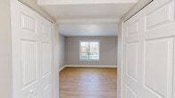 This single-floor residence offers a clean, modern aesthetic throughout, characterized by a neutral color palette, light wood-style flooring, and crisp white trim that create a cohesive and welcoming atmosphere. The kitchen serves as a functional centerpiece, featuring dark cabinetry contrasted against light quartz countertops, a stainless steel undermount sink, and a full suite of stainless steel appliances including a refrigerator, electric range, microwave, and dishwasher. A peninsula counter provides additional prep space and naturally defines the transition between the kitchen and the adjoining living area. The bedrooms are well-proportioned and filled with natural light from windows fitted with horizontal blinds. One bedroom features light wood-style flooring and double closet doors, while another is finished with plush neutral carpeting, offering a softer underfoot feel. A third flexible room with wood-style flooring provides additional living or sleeping space. The bathroom is finished with light wood-style flooring, a white vanity with an integrated sink, and brushed nickel fixtures, maintaining the clean and consistent style found throughout. The overall layout, as seen in the floor plan, is thoughtfully organized for efficient flow between spaces.
