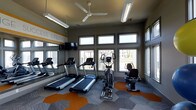 This well-appointed fitness center is designed to provide a comprehensive cardio workout experience in a bright, energizing environment. The space features a collection of cardio machines, including multiple treadmills, an elliptical trainer, and a recumbent stationary bike, catering to a variety of fitness preferences and ability levels. A wall-mounted flat-screen TV accompanies the equipment, allowing members to stay entertained during their workouts. Large, floor-to-ceiling windows along one wall flood the space with natural light and offer open views of the surrounding outdoor area, creating an inviting atmosphere that helps motivate activity. A ceiling fan overhead ensures comfortable air circulation throughout the room. The flooring features a distinctive patterned carpet with bold orange hexagonal accents set against a gray background, adding a dynamic visual element to the space. Full-length mirrors on one wall enhance the sense of openness while allowing users to monitor their form. The walls are painted in a contemporary gray tone with a bold yellow "Fitness Lifestyle" graphic accent, reinforcing the health-focused purpose of the space. The overall design is clean, modern, and functional — ideal for supporting an active lifestyle.