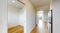 Located in Vancouver's vibrant Mount Pleasant neighbourhood, this contemporary two-storey home offers a thoughtfully designed layout across two compact yet functional floors. Light hardwood flooring runs throughout the entire space, lending warmth and continuity to the clean, modern aesthetic defined by crisp white walls and minimalist finishes.

The kitchen is a standout feature, equipped with stainless steel appliances including a full-size refrigerator and range, sleek grey cabinetry, white countertops, and a striking yellow subway tile backsplash that adds a bold pop of colour. A frosted glass door provides privacy while maintaining a sense of openness.

The three bedrooms vary in character and scale. The generously proportioned primary bedroom occupies a significant portion of the upper floor and features a wide picture window framing views of the surrounding Vancouver skyline and cityscape, flooding the room with natural light. The additional bedrooms offer quieter, well-lit spaces with hardwood floors and white walls, one of which features angled ceilings that add architectural interest. A well-connected hallway ties the rooms together and provides glimpses of outdoor greenery. The overall ambiance is bright, clean, and modern — well-suited for urban living in one of Vancouver's most walkable communities.