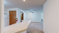 Located at 2234 Luann Ln in Madison, Wisconsin, this single-floor residence offers two bedrooms and two full bathrooms within a well-organized, functional layout. The combined kitchen and living area serves as the heart of the home, featuring an open-concept design with a peninsula counter that separates the kitchen from the living space. The kitchen is equipped with white cabinetry trimmed in warm wood tones, ample counter space, white appliances including a range and refrigerator, and tile flooring that flows throughout the wet areas. The living room is carpeted and bright, highlighted by a sliding glass door with vertical blinds that opens to a view of mature trees, filling the space with natural light. Both bedrooms are carpeted and generously sized, with the primary bedroom offering notable square footage, natural light from a window, and access to closet space via warm wood-toned doors. The two bathrooms are similarly appointed, each featuring a tub/shower combination with grab bars, a vanity with extended countertop and storage cabinetry below, and durable tile flooring. Textured ceilings are consistent throughout the home, and warm wood baseboards and door trims add a cohesive finishing touch across all rooms.