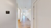 This well-appointed 2-bedroom, 2-bathroom unit is thoughtfully designed with a modern aesthetic and efficient single-floor layout. Light-toned hardwood flooring flows consistently throughout the space, complementing the clean white walls and crisp trim work that define each room.

The open-concept kitchen and living area serves as the heart of the unit. The kitchen is outfitted with white flat-panel cabinetry, a large waterfall-edge island with an integrated sink, stainless steel appliances including a refrigerator, electric range, and over-range microwave, and recessed lighting accented by pendant fixtures. Large black-framed windows in the kitchen flood the space with natural light and offer elevated views of the surrounding treetops and neighborhood.

A central hallway connects the bedrooms and bathrooms, maintaining a clean flow throughout the unit. Both bedrooms are generously proportioned, featuring large black-framed windows that bring in abundant natural light and provide open views of the surrounding cityscape and greenery. The primary bedroom includes a closet with built-in shelving.

The two bathrooms offer distinct configurations: one features a full soaking tub with tiled surround, while the other includes a glass-enclosed walk-in shower. Both are finished in crisp white with chrome fixtures, maintaining the unit's clean, contemporary character.