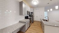 Located at 2571 Seminole Trail in Charlottesville, Virginia, this single-floor unit offers a thoughtfully designed open-concept layout that seamlessly connects the living and kitchen areas. The kitchen is a standout feature, showcasing gray shaker-style cabinetry, granite countertops, a subway tile backsplash, and a full suite of stainless steel appliances including a refrigerator, range, and microwave. A central island with an undermount sink and pendant lighting adds both functionality and visual appeal, while warm hardwood flooring grounds the space with an inviting feel.

The open living area extends from the kitchen, finished with neutral carpet and ceiling fans that enhance comfort and airflow. Track lighting along one wall provides flexible illumination throughout. The bedrooms are carpeted and well-lit by natural light through double windows fitted with blinds, each room also featuring a ceiling fan.

The bathrooms are finished consistently with the kitchen's aesthetic, incorporating gray vanity cabinetry, granite countertops, and hardwood flooring. One bathroom includes a tub-shower combination and access to a walk-in closet, offering practical storage. The overall palette throughout the unit is bright and neutral, creating a clean, modern ambiance well-suited to the Charlottesville setting.