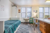 Located at 517 N Lake St in Madison, Wisconsin, this efficiently designed studio unit offers a practical and functional single-floor layout. The open-concept living and sleeping area features hardwood-style flooring and multiple windows fitted with blinds, allowing natural light to brighten the space throughout the day. A window-unit air conditioner provides climate control, while a radiator offers supplemental heating.

The kitchen is a standout feature, offering generous cabinetry with warm wood-toned finishes, white appliances including a refrigerator, electric range, microwave, and dishwasher, along with tile flooring and under-cabinet lighting. A peninsula counter with seating extends into the main living area, serving as a natural divider between the kitchen and the rest of the space.

The sleeping area accommodates a full-sized bed and includes a wardrobe unit with additional shelving, providing ample storage within the compact footprint. The full bathroom includes a tub/shower combination with built-in shelving, a vanity with wood cabinetry, and tile flooring, maintaining a clean, functional aesthetic. Overall, the unit is thoughtfully arranged to maximize utility while maintaining a comfortable, livable atmosphere.