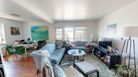 Located at 5619 5th Ave in Pittsburgh's Shadyside neighborhood, this two-bedroom, one-bathroom residence offers a functional and comfortable single-floor layout. The living room serves as the heart of the home, featuring warm hardwood flooring, large windows that invite generous natural light, and a balcony view that opens to the surrounding neighborhood. The space accommodates a full seating arrangement with room for entertainment. The galley-style kitchen is equipped with warm oak cabinetry extending to the ceiling, a gas range, dishwasher, tile flooring, and a window that adds additional brightness. Both bedrooms feature hardwood floors and multiple windows providing ample natural light. The primary bedroom offers a comfortable footprint with closet access, while the second bedroom is similarly well-lit with windows on multiple walls. A hallway connects the rooms with clean, neutral walls and a runner-ready floor. The bathroom retains a classic retro character, showcasing vintage tilework with a bold red accent border, a pedestal sink, and a tub-shower combination. The overall layout is efficiently organized, making thoughtful use of every room in a well-connected floor plan.