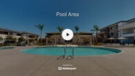 Located at 25150 Jefferson Ave in Murrieta, California, this outdoor amenity space showcases a resort-inspired design tailored for relaxation and recreation under the Southern California sun. The centerpiece is a generously sized, kidney-shaped swimming pool with crystal-clear blue water, complemented by a separate spa for unwinding. Surrounding the pool, a broad concrete deck provides ample space for lounge chairs and seating, ideal for sunbathing or socializing. Multiple pergola-style shade structures with clean, modern lines are positioned throughout the area, offering sheltered spots with patio furniture and market umbrellas. The space is framed by tall, elegant palm trees that enhance the resort atmosphere and provide a sense of privacy. A secure black iron gate with stone accent pillars marks the entrance, reflecting a well-maintained and gated community environment. The multi-story residential buildings surrounding the courtyard feature a contemporary architectural style with neutral stucco exteriors, balconies, and dark-trimmed windows. Thoughtfully placed landscaping with manicured shrubs and ground cover ties the entire outdoor space together, creating a cohesive and inviting community amenity area perfectly suited to the warm Murrieta climate.