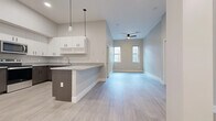 This single-floor unit presents a contemporary design with a cohesive neutral color palette of soft grays and whites throughout. The open-concept layout seamlessly connects the kitchen and living area, creating a spacious, airy feel enhanced by light wood-look flooring. The kitchen is well-appointed with crisp white upper cabinetry, contrasting dark wood-tone lower cabinets, granite countertops, and a peninsula that doubles as a breakfast bar. Stainless steel appliances, including a refrigerator, range, microwave, and dishwasher, complete the functional cooking space. Pendant lighting above the peninsula adds a modern accent. The living area benefits from natural light provided by a pair of windows and is equipped with a ceiling fan overhead.

Multiple bedrooms feature plush carpeting, ample natural light from individual windows, and dedicated closet space. At least one bedroom includes a walk-in style closet with built-in racking. The bathroom is finished with tile flooring, a granite-topped vanity with dark wood cabinetry, and a full tub-shower combination. Throughout the unit, tall ceilings, clean white baseboards, and a consistent modern aesthetic contribute to a bright and well-designed living environment.