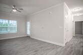 Located on Scots Pine Run in North Chesterfield, Virginia, this single-floor residence offers a well-designed, open layout with a clean, contemporary aesthetic throughout. The living area is spacious and bright, featuring light-toned vinyl plank flooring, crown molding, a ceiling fan, and large windows with blinds that allow ample natural light to fill the room. A door provides direct outdoor access, enhancing the sense of openness. The kitchen is thoughtfully appointed with rich dark-stained cabinetry, granite-look countertops, and black and stainless steel appliances including a range, microwave, and refrigerator. The galley-style layout maximizes functionality while maintaining a polished look. The bedrooms are carpeted for comfort and each include ceiling fans. One bedroom features a window with outdoor views, while another includes access to a spacious walk-in closet outfitted with wire shelving for organized storage. The bathroom includes a full tub and shower combination with clean white surround tile, brushed nickel fixtures, and a vanity with matching dark cabinetry. A dedicated laundry nook with washer/dryer hookups adds everyday convenience. Light neutral tones, white trim, and consistent finishes create a cohesive and welcoming atmosphere throughout the entire space.