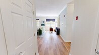 This single-floor, 2-bedroom, 2-bathroom residence offers a well-organized layout with a seamless flow between its key living spaces. The open-concept kitchen is a standout feature, showcasing white shaker cabinetry with gold hardware, sleek marble-look countertops, a large peninsula with an undermount sink, and stainless steel appliances including a refrigerator, range, microwave, and dishwasher. Light wood-style flooring runs throughout, lending a cohesive and airy feel to the entire unit. The living room is generously proportioned, featuring crown molding, a fireplace, track lighting, and multiple windows that invite abundant natural light. A dedicated dining nook adds functional versatility to the space. The primary bedroom is a comfortable retreat with sliding glass doors opening to a private balcony overlooking a lush green outdoor area, complemented by a ceiling fan. The second bedroom also features a ceiling fan and ample natural light. Both bathrooms are finished with white cabinetry, dark countertops, tub-shower combinations with classic tile accents, and wood-style flooring. Two closets provide practical storage solutions throughout the residence.