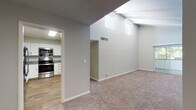 This single-floor residence offers a thoughtfully designed layout with a mix of modern finishes and comfortable living spaces. The living area is a standout, boasting soaring vaulted ceilings with exposed beams and elevated clerestory windows that flood the space with natural light. Soft, neutral-toned carpet flows throughout the living and bedroom areas, complementing the warm hardwood-style flooring found in the kitchen and bathroom.

The kitchen is well-equipped, featuring crisp white shaker cabinetry with matte black hardware, granite countertops, a stainless steel undermount sink, and a full suite of stainless steel appliances including a range, built-in microwave, and dishwasher. The space is functional and stylish, ideal for everyday cooking.

The bathroom showcases a clean, contemporary aesthetic with large-format white wall tiles surrounding a soaking tub and shower combination, accented by matte black fixtures. The vanity area features a granite countertop, an undermount sink, white cabinetry, and a backlit LED mirror that adds a refined touch.

The bedrooms are generously proportioned, with plush carpet, neutral walls, and windows providing natural light. The entry area benefits from the dramatic vaulted ceiling and opens seamlessly into the main living space, creating an airy, welcoming atmosphere throughout.