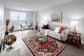 Located on the 12th floor at 123 Charlton Ave E in Hamilton, Ontario, this well-appointed one-bedroom, one-bathroom unit offers a thoughtfully designed layout that maximizes its efficient footprint. Light wood laminate flooring runs throughout, lending a warm, cohesive feel to the entire space.

The open-concept kitchen and living area form the heart of the unit. The kitchen features white shaker-style cabinetry with ample storage, crisp white quartz countertops, a subway tile backsplash with under-cabinet lighting, stainless steel appliances, and a peninsula with bar seating for two — ideal for casual dining or entertaining. The adjacent living room is bright and inviting, with neutral walls and generous space for comfortable furnishings.

The bedroom is a comfortable retreat, accommodating a queen-sized bed with room to spare. It features a large sliding-door closet and a window that frames city views, filling the room with natural light. The full bathroom is clean and functional, finished with white subway tile surrounding a full-sized soaker tub and shower combination, complemented by a white vanity and wood-look flooring.

A mini-split HVAC unit provides year-round climate control, and the overall design aesthetic — crisp whites, soft neutrals, and modern finishes — gives the unit a fresh, contemporary character throughout.