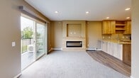 Located at 1130 County Road 4 in St. Cloud, Minnesota, this efficiently designed single-floor unit offers a thoughtful layout that maximizes every square foot. The open-concept kitchen and living area serves as the heart of the space, where light wood cabinetry, granite countertops, and stainless steel appliances — including an electric range, microwave, and dishwasher — create a functional and modern kitchen. Wood-look vinyl plank flooring runs throughout the kitchen and entry areas, transitioning to plush carpet in the living room. A striking tiled fireplace with a built-in niche serves as the focal point of the living area, which is bathed in natural light from a large picture window and sliding glass door that opens to a private balcony with outdoor views. The bathroom features tile flooring, a wood vanity with granite countertop, and a walk-in shower. A dedicated laundry area includes a full-size Whirlpool washer and dryer. An additional carpeted room, accessible via a sliding barn door, offers flexible use and includes a wall-mounted mini-split unit for supplemental climate control. Recessed lighting, warm taupe walls, and a blue accent entry door complete the clean, contemporary aesthetic throughout.