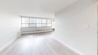 Located at 65 Thorncliffe Park Dr in Toronto's Thorncliffe Park neighbourhood, this well-appointed 1-bedroom, 1-bathroom unit offers a thoughtfully designed layout across a single floor. Light-toned luxury vinyl flooring runs throughout, lending a clean and contemporary feel to every room.

The spacious living room is bathed in natural light through a wide bank of floor-to-ceiling windows fitted with baseboard heating, offering expansive views of the surrounding cityscape. A private balcony, accessible from the living area, extends the living space outdoors.

The galley-style kitchen is efficiently designed with ample white cabinetry, marble-look countertops, and stainless steel appliances including a refrigerator, electric range, and double-basin sink — providing generous storage and prep space.

The generously sized primary bedroom features a large sliding-door closet and a window with natural light, creating a calm and comfortable retreat. A second hallway area offers additional storage access.

The bathroom is finished with marble-style tile surrounding the full soaker tub and shower, complemented by a vanity with matching countertop and tile flooring, maintaining the cohesive, modern aesthetic found throughout the unit. Two connecting hallways ensure smooth flow between all areas of the home.