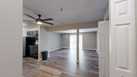 Located at 1800 Park West Blvd in Griffith, Indiana, this 2-bedroom, 1-bathroom residence offers a practical and comfortable single-floor layout. The combined living and dining area forms the heart of the home, featuring rich hardwood-style flooring, neutral gray-toned walls, and a ceiling fan that enhances the open, airy feel. Vertical blinds line a large sliding glass door, flooding the space with natural light. The kitchen is positioned adjacent to the living area, featuring dark cabinetry and an efficient design. A dining area flows naturally between the kitchen and living space. Both bedrooms are carpeted and share a soft, neutral palette. The primary bedroom is generously sized, offering two windows with outdoor views of surrounding greenery, a wall-mounted AC unit, and a full-width bifold closet for ample storage. The second bedroom also features a bifold closet and a bright window. A shared full bathroom includes a tub/shower combination with clean white tile finishes and wood-style flooring. Additional storage is provided by a dedicated closet with built-in shelving. Baseboard heating is present throughout, ensuring year-round comfort in this well-maintained Griffith residence.