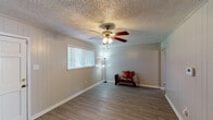 Located at 915 South College Road in Lafayette, Louisiana, this single-floor home offers a practical and comfortable layout designed for everyday living. The main living area greets you with durable wood-look flooring, neutral-toned vertical panel walls, and a textured ceiling complete with a classic ceiling fan and light fixture. A wide window allows natural light to fill the space, creating a bright and welcoming atmosphere. An adjacent area serves as a second living or flex space, featuring the same flooring and another ceiling fan, with a large window overlooking the outdoors. The kitchen is well-appointed with warm honey-toned wood cabinetry, dark granite-style countertops, a double stainless steel sink, and ample upper and lower cabinet storage. The bedrooms are carpeted for comfort, each equipped with ceiling fans and offering a calm, neutral palette with generous floor space. The bathroom includes a full tub-shower combination, toilet, vanity with white cabinetry, wood-look flooring, and a high window for natural ventilation and light. The overall layout is efficient and cohesive, making this Lafayette home a solid and functional residence.
