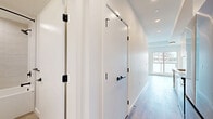 Located at 325 Royal Commons in Victoria, BC, Unit 315 is a modern one-bedroom, one-bathroom residence designed with clean lines and a bright, contemporary aesthetic. The open-concept living and kitchen area is anchored by warm-toned luxury vinyl plank flooring that flows throughout the entire unit. The kitchen features white cabinetry, a stainless steel appliance package, and a sleek sink with matte black fixtures, all neatly integrated along one wall. A wall-mounted mini-split heating and cooling unit ensures year-round comfort, while recessed lighting brightens the space efficiently. A stylish sliding barn door with black hardware provides a modern touch as it opens to the bedroom, which offers a built-in closet with sliding doors and ample natural light. The living area is highlighted by a tray ceiling detail and a large window paired with a sliding glass door that opens to a private balcony, offering views of the surrounding neighbourhood. The bathroom is finished with large-format wall tile surrounding the soaker tub and shower, complemented by a white vanity with a quartz countertop, undermount sink, and matte black hardware throughout. The overall ambiance is clean, modern, and move-in ready.