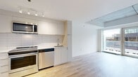 Located at 1020 Rue de Bleury in the heart of downtown Montréal, this modern one-bedroom, one-bathroom unit offers a well-designed open-concept layout finished with contemporary details throughout. Light hardwood flooring flows seamlessly across the living, dining, and kitchen areas, creating a bright and cohesive feel.

The kitchen is efficiently appointed with sleek white cabinetry, a white subway tile backsplash, and a full suite of stainless steel appliances including a refrigerator, electric range, built-in microwave, and dishwasher. Track lighting overhead adds both function and a modern touch. The kitchen opens directly into the dining and living areas, making the space feel open and connected.

The living room benefits from floor-to-ceiling sliding glass doors that invite abundant natural light and provide access to an outdoor area with city views. The bedroom is a compact, well-proportioned room with a casement window framing views of the surrounding Montréal cityscape and an exposed concrete ceiling that adds an industrial character. A dedicated closet offers practical storage.

The bathroom features large-format neutral tile, a walk-in shower, a floating vanity with an integrated sink, and a mirrored medicine cabinet, rounding out this clean and modern urban residence.