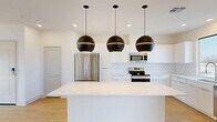 Located in Palm Desert, CA, this thoughtfully designed 2-bedroom, 2-bathroom residence offers a well-appointed single-floor layout. The open-concept kitchen serves as the heart of the home, showcasing a striking waterfall quartz island beneath a pair of bold matte black globe pendant lights. White shaker-style cabinetry extends to the ceiling, complemented by a geometric tile backsplash and a full suite of stainless steel appliances, including a French door refrigerator, range, microwave, and dishwasher. Light wood-look flooring flows seamlessly throughout the main living area, enhancing the bright, airy atmosphere created by recessed lighting and natural light from multiple windows. A private balcony offers outdoor access directly from the living space. The spacious primary bedroom features a ceiling fan, hardwood-style flooring, and a dedicated balcony access door. The secondary bedroom is carpeted and includes a built-in closet with shelving. Both bathrooms are finished with clean white cabinetry, undermount sinks, large mirrors, and tub-shower combinations with tile surrounds. The residence also includes a dedicated closet for additional storage, rounding out a functional and modern living space.