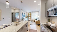 Located at 1331 Chester Ave in Raleigh's desirable 27608 zip code, this single-floor residence showcases a contemporary design with a warm, cohesive aesthetic throughout. Light hardwood flooring flows seamlessly across the open-concept layout, complemented by recessed lighting and a neutral color palette that creates an airy, inviting atmosphere.

The kitchen is a standout feature, offering gray shaker-style cabinetry, stainless steel appliances including a French door refrigerator and range, a white subway tile backsplash, a matte black fixture sink, and a generous island with quartz countertops and pendant lighting — ideal for both cooking and casual dining.

The living area is bright and welcoming, anchored by a warm-toned wood front door with glass panels that invite natural light, alongside a large window with sheer curtains. A dedicated mudroom nook with a built-in bench and wall hooks provides practical entryway storage.

The bedroom is a serene retreat, featuring a ceiling fan, natural light from a well-dressed window, and ample space. A walk-in closet with built-in shelving and hanging storage adjoins the room, while a full bathroom with gray vanity cabinetry, a large mirror, and tile flooring completes the private quarters. A stacked laundry area adds everyday convenience.