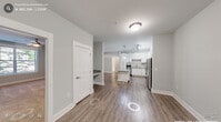 This well-appointed 3-bedroom, 2-bathroom single-story home in Apex, NC offers a clean, modern aesthetic throughout. The open-concept kitchen and living area serves as the heart of the home, featuring crisp white shaker cabinetry, granite countertops, a subway tile backsplash, a center island, and stainless steel appliances including a refrigerator and range. Warm wood-look flooring flows seamlessly through the main living areas, adding continuity and warmth to the neutral gray color palette.

The three bedrooms are carpeted for comfort, each equipped with a ceiling fan and generous closet space. The spacious primary bedroom includes access to a well-sized walk-in closet with wire shelving. The primary bathroom is highlighted by a double-sink vanity with granite countertops, large-format tile flooring, and accessibility-friendly fixtures. The second bathroom features a tiled tub-and-shower combination, granite vanity, and tile flooring. A dedicated laundry room with a full-size washer and dryer adds everyday convenience. Multiple closets and hallways provide ample storage throughout. The layout is efficient and functional, making excellent use of the available space for comfortable single-floor living.