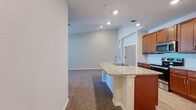 Located at 2796 Spring Orchard Ave in Mt Dora, Florida, this single-story home offers a well-designed open-concept layout that seamlessly connects the kitchen and living areas. The kitchen is a standout feature, equipped with rich warm-toned cabinetry, granite countertops, a subway tile backsplash, and a full suite of stainless steel appliances including a refrigerator, range, and microwave. A central kitchen island with a granite surface and integrated sink provides additional workspace and serves as a natural gathering point between the kitchen and the adjacent living area. The living space features neutral-toned carpet and recessed lighting, creating a bright and welcoming atmosphere. The bedroom is generously proportioned, carpeted for comfort, and includes a ceiling fan and a dedicated walk-in closet with built-in shelving for ample storage. A window in the bedroom allows for natural light. The bathroom is finished with wood-look tile flooring, a granite-topped vanity with warm wood cabinetry, and a full tub-shower combination with white subway tile surround. Throughout the home, clean neutral walls, consistent finishes, and thoughtful detailing contribute to a cohesive and move-in-ready interior.