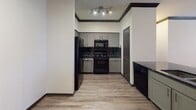 Located at 13333 West Rd in Houston, Texas, this thoughtfully designed single-floor residence blends modern style with functional living. The entryway welcomes you with rich hardwood-style flooring, crisp white walls, and striking dark crown molding that carries throughout the home, creating a cohesive and polished aesthetic.

The living room is an inviting, generously sized space bathed in natural light from large windows dressed with floor-length drapes. A ceiling fan adds comfort, while the warm tones of the area rug and neutral furnishings contribute to the room's relaxed yet refined atmosphere.

The galley-style kitchen is well-equipped, featuring white cabinetry, dark granite countertops, black subway tile backsplash, and black appliances. Crown molding and track lighting complete the sleek, contemporary look.

The bedrooms are spacious and serene, each carpeted for comfort and fitted with ceiling fans and large windows. The primary bedroom offers direct access to a private exterior door, mirrored sliding closets, and ample room to unwind. A second bedroom mirrors this comfortable design.

The bathroom is clean and functional, offering a dual-sink vanity with dark granite counters, wood-style flooring, a soaking tub, and a large mirror — delivering a spa-like finishing touch to this well-rounded Houston residence.
