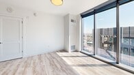 Located in the heart of downtown Austin at 501 Brazos St, this contemporary three-bedroom, two-bathroom high-rise residence offers a thoughtfully designed open-concept layout with premium finishes throughout. Light wood-tone flooring flows seamlessly across the entire space, complementing the clean white walls and modern aesthetic.

The combined kitchen and living area serves as the centerpiece of the home. The chef's kitchen features a large waterfall island with an undermount sink, rich dark wood cabinetry extending to the ceiling, white quartz countertops, stainless steel appliances, and track lighting. Floor-to-ceiling windows flood the living area with natural light and frame breathtaking panoramic views of the Austin skyline.

Each of the three bedrooms offers generous proportions, with large windows or full-height glazing showcasing elevated city views. The primary bedroom includes a ceiling fan and direct access to the en-suite bath. The primary bathroom is particularly striking, featuring a walk-in glass shower clad in dark stone-look tile, a double vanity with white cabinetry and matte black hardware, and wood-look tile flooring. The second bathroom offers a soaking tub with full-height stone tile surround and matching matte black fixtures. A hallway and dedicated closet complete this well-appointed urban residence.