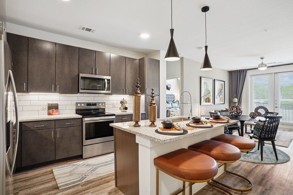 Kitchen with espresso cabinetry, speckled granite countertops, white tile backsplash, stainless steel appliances, and hard surface flooring - Avalon Castle Hills