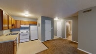Located at 2614 E Fountain Blvd in Colorado Springs, Colorado, this single-floor unit offers a practical and straightforward layout designed for comfortable everyday living. The open living area is finished with wall-to-wall carpet in a warm tan hue and painted in neutral gray tones, creating a clean and cohesive aesthetic throughout. A textured ceiling adds a classic touch to the interior. The living space receives natural light through a window fitted with vertical blinds, contributing to a bright and airy feel. The kitchen is efficiently arranged with warm oak cabinetry offering ample upper and lower storage, light-toned countertops, and durable vinyl tile flooring. White appliances — including a coil-top electric range with an overhead exhaust hood and a full-size refrigerator — provide all essential cooking and food storage functions. Adjacent to the kitchen, additional cabinetry and counter space extend into the dining or utility area, adding to the overall storage capacity. The bedroom is a generously sized, carpeted room with a window that allows natural light to filter in. The full bathroom includes a tiled shower-tub combination with a curtain rod, a single-sink vanity with cabinet storage below, a medicine cabinet mirror, and overhead lighting. Interior doors throughout are classic six-panel white designs, adding a consistent architectural detail to the unit.