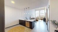 Located at 55 Elm Street in Hartford, CT, this one-bedroom, one-bathroom unit offers a well-designed open-concept layout that seamlessly connects the kitchen, dining, and living areas. The living room immediately impresses with soaring ceilings and oversized grid-pane windows that flood the space with natural light while framing city views. A wall-mounted split system provides climate control alongside classic cast-iron radiators.

The kitchen is outfitted with dark cabinetry accented by gold hardware, a full suite of stainless steel appliances including a large French door refrigerator, and a central island with a white quartz countertop and pendant lighting — ideal for both cooking and casual dining. The adjacent dining area, lit by a complementary pendant fixture, provides comfortable space for a full table.

The spacious bedroom features large grid windows with city views, soft carpeting, and a wall-mounted split unit, creating a calm and comfortable retreat. A dedicated closet adds practical storage.

The bathroom showcases striking dark hexagonal floor tile, a walk-in glass-panel shower with black fixtures, and a clean vanity with white countertop. The unit's neutral palette, modern architectural details, and thoughtful layout make it a refined and functional urban residence.