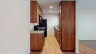 Located at 532 Broadway in El Cajon, California, this single-floor residence offers a functional and comfortable layout with thoughtful finishes throughout. The kitchen is a standout feature, showcasing rich warm-toned wood cabinetry extending floor to ceiling, granite countertops, hardwood flooring, recessed lighting, and black appliances including a range, microwave, refrigerator, and sink — providing ample storage and a practical cooking space. The living area is carpeted and bright, featuring a sliding glass door with vertical blinds that allows natural light to filter in and provides access to an outdoor area. A wall-mounted HVAC unit ensures year-round comfort. An adjacent dining or entry area connects seamlessly to the kitchen, maintaining an open, accessible flow. The bedroom is generously sized with plush carpeting, a ceiling fan with integrated lighting, a window with vertical blinds for natural light, and a spacious walk-in closet offering excellent storage. The bathroom is well-equipped with a granite-topped vanity, warm wood cabinetry, a large mirror, and a full tub-shower combo, all set on hardwood-style flooring. The overall ambiance is clean, neutral, and move-in ready.