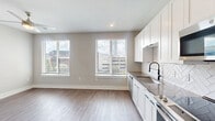 Located at 2801 Windy Ridge Pkwy SE in Smyrna, GA, this well-appointed one-bedroom, one-bathroom residence offers a clean, modern aesthetic throughout. The open-concept kitchen and living area serves as the heart of the home, featuring light wood-look flooring, recessed lighting, and multiple windows that allow natural light to fill the space. The kitchen is outfitted with crisp white shaker-style cabinetry, dark quartz countertops, a black matte faucet, stainless steel appliances including a range, microwave, and dishwasher, and a striking herringbone-patterned tile backsplash that adds visual texture. The bedroom is carpeted for comfort and includes a dedicated walk-in closet, a ceiling fan, and a window with urban views. A stylish hallway with barn-style doors connects the main areas, and a utility panel is conveniently accessible along the corridor. The bathroom features a wide vanity with dark countertops, white cabinetry with matte black hardware, a framed mirror, and a sleek glass-enclosed shower. Neutral tones and contemporary finishes are carried consistently throughout, creating a cohesive and functional living environment suited for modern urban living in the Smyrna area.