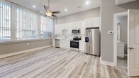 Located at 225 Park Ave in Baltimore, MD, this thoughtfully designed one-bedroom, one-bathroom unit offers a clean, modern aesthetic throughout its efficiently organized single-floor layout. Light gray walls, crisp white trim, and durable wood-look plank flooring create a cohesive, contemporary feel across every room.

The open-plan living and kitchen area serves as the heart of the unit, bathed in natural light through large windows dressed with vertical blinds. A ceiling fan with recessed lighting adds both comfort and style. The kitchen is well-appointed with tall white shaker cabinetry, a classic subway tile backsplash, light quartz countertops, and a full suite of stainless steel appliances including a refrigerator with ice maker, electric range, over-the-range microwave, and dishwasher.

The bedroom is a comfortable, well-proportioned retreat featuring the same plank flooring, neutral gray walls, and a ceiling fan. It provides direct access to a dedicated laundry room housing a stacked GE washer and dryer unit alongside the water heater and HVAC system — a practical and convenient amenity.

The bathroom is finished with white subway tile in a walk-in shower with sliding glass doors, paired with clean, modern fixtures. Every detail of this unit reflects a fresh, move-in-ready standard ideal for urban living in downtown Baltimore.
