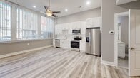 Located at 225 Park Ave in Baltimore, MD, this thoughtfully designed one-bedroom, one-bathroom unit offers a clean, modern aesthetic throughout its efficiently organized single-floor layout. Light gray walls, crisp white trim, and durable wood-look plank flooring create a cohesive, contemporary feel across every room.

The open-plan living and kitchen area serves as the heart of the unit, bathed in natural light through large windows dressed with vertical blinds. A ceiling fan with recessed lighting adds both comfort and style. The kitchen is well-appointed with tall white shaker cabinetry, a classic subway tile backsplash, light quartz countertops, and a full suite of stainless steel appliances including a refrigerator with ice maker, electric range, over-the-range microwave, and dishwasher.

The bedroom is a comfortable, well-proportioned retreat featuring the same plank flooring, neutral gray walls, and a ceiling fan. It provides direct access to a dedicated laundry room housing a stacked GE washer and dryer unit alongside the water heater and HVAC system — a practical and convenient amenity.

The bathroom is finished with white subway tile in a walk-in shower with sliding glass doors, paired with clean, modern fixtures. Every detail of this unit reflects a fresh, move-in-ready standard ideal for urban living in downtown Baltimore.