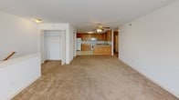 This single-floor residence offers a well-organized, open-concept layout that connects the living areas and kitchen seamlessly. The kitchen is a functional centerpiece, featuring warm honey-toned oak cabinetry with ample upper and lower storage, light-toned countertops, and white appliances including a gas range, refrigerator, built-in microwave, and dishwasher. The flooring throughout the kitchen is finished in classic white ceramic tile, providing a clean, easy-to-maintain surface. The living areas are carpeted in a neutral beige tone that extends throughout the bedrooms, creating a cohesive and comfortable feel. A ceiling fan with a light fixture serves the main living area, adding both function and airflow. The bedrooms are bright and generously proportioned, with large windows that invite natural light and offer views of lush greenery outside. Closet space is included for added storage convenience. The bathroom is finished in a clean, all-white palette, complete with a single-sink vanity with a wide mirror, a full tub-shower combination, and white tile flooring. Throughout the space, white walls and crisp trim contribute to a bright, neutral aesthetic that is move-in ready and highly versatile.
