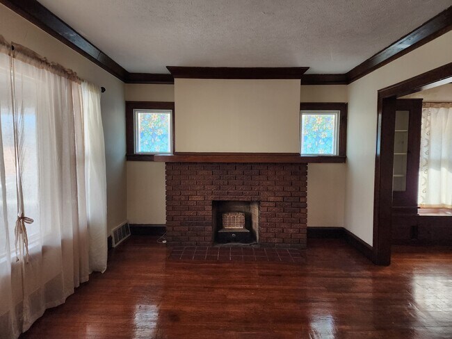 Sala de estar luminosa y acogedora con pisos de madera y chimenea decorativa. - 1382 Webb Rd