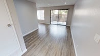 This well-appointed single-floor unit offers a clean, modern aesthetic throughout, with fresh neutral-toned walls and durable wood-look laminate flooring running seamlessly across all main living areas. The spacious living room is bathed in natural light from a large window and a sliding glass door that opens to a private balcony, providing pleasant outdoor views. Recessed lighting and a textured ceiling add depth and warmth to the space.

The kitchen is efficiently laid out with crisp white cabinetry, granite-style countertops, a double stainless steel sink, stainless steel appliances including a gas range and refrigerator, and recessed lighting overhead. It connects openly to the dining and living areas, creating a cohesive, functional flow.

Both bedrooms are comfortably sized, each featuring wood-look flooring, ceiling fans with integrated lighting, and windows dressed with vertical blinds that invite natural light. One bedroom includes a set of sliding-door closets, offering generous storage.

The full bathroom is neatly finished with a granite-style vanity countertop, a dual-basin sink, a large mirror, and a clean tub-shower combination. Throughout the unit, white baseboards and recessed lighting contribute to a bright, well-maintained interior.