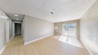 Located at 2255 E Sunset Rd in Las Vegas, NV, this single-floor unit offers a clean, modern aesthetic throughout. Light wood-style flooring runs consistently across the living spaces, complemented by neutral gray-toned walls and crisp white baseboards that create a bright, cohesive atmosphere.

The living area is generously proportioned, bathed in natural light streaming through a full-width sliding glass door that opens to an outdoor area. A textured ceiling adds subtle dimension to the space.

The kitchen is a standout feature, outfitted with slate-gray shaker-style cabinetry extending to the ceiling for ample storage, stainless steel appliances including a refrigerator, range, and dishwasher, as well as a gray quartz-style countertop. Recessed lighting illuminates the workspace effectively.

The bedrooms are well-sized and filled with natural light from horizontal-slatted windows. One bedroom includes a ceiling fan with light fixture, while another features a set of sliding panel closet doors with a paneled design. An additional flexible room provides further utility.

The bathroom is finished with white cabinetry, a granite-style countertop, an undermount sink, and an illuminated mirror, alongside a full tub-shower combination. The unit's consistent finishes and thoughtful layout make it a functional and attractive space in the heart of Las Vegas.