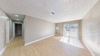 Located at 2255 E Sunset Rd in Las Vegas, NV, this single-floor unit offers a clean, modern aesthetic throughout. Light wood-style flooring runs consistently across the living spaces, complemented by neutral gray-toned walls and crisp white baseboards that create a bright, cohesive atmosphere.

The living area is generously proportioned, bathed in natural light streaming through a full-width sliding glass door that opens to an outdoor area. A textured ceiling adds subtle dimension to the space.

The kitchen is a standout feature, outfitted with slate-gray shaker-style cabinetry extending to the ceiling for ample storage, stainless steel appliances including a refrigerator, range, and dishwasher, as well as a gray quartz-style countertop. Recessed lighting illuminates the workspace effectively.

The bedrooms are well-sized and filled with natural light from horizontal-slatted windows. One bedroom includes a ceiling fan with light fixture, while another features a set of sliding panel closet doors with a paneled design. An additional flexible room provides further utility.

The bathroom is finished with white cabinetry, a granite-style countertop, an undermount sink, and an illuminated mirror, alongside a full tub-shower combination. The unit's consistent finishes and thoughtful layout make it a functional and attractive space in the heart of Las Vegas.