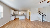 Located at 2314 Doveshell Dr in North Myrtle Beach, SC, this two-story home offers a thoughtfully designed layout spread across two well-proportioned floors. The main level features a bright, open-concept living, dining, and kitchen area with warm light hardwood flooring and abundant natural light from multiple windows. The kitchen is a standout, showcasing granite countertops, crisp white shaker cabinetry, stainless steel appliances including a French door refrigerator, a central island with pendant lighting, and a dedicated pantry for additional storage. A convenient half bathroom and laundry room round out the first floor, along with a patio for outdoor enjoyment. A staircase with a classic black baluster railing leads to the upper level, where both bedrooms are located. The spacious primary bedroom features plush carpeting, a ceiling fan, a walk-in closet, and a private en-suite bathroom. The second bedroom is equally comfortable, also appointed with carpet and a ceiling fan. Two additional full bathrooms, one of which features a tub-shower combination with granite vanity, serve the upper floor. Throughout the home, neutral tones and clean finishes create a cohesive, move-in-ready aesthetic.