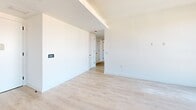 Located in East Harlem at 205 E 110th Street, this thoughtfully designed 2-bedroom, 2-bathroom residence offers a clean, contemporary aesthetic throughout. Light-toned hardwood flooring runs continuously across the single-level layout, creating a cohesive and airy feel.

The open kitchen and living area is anchored by a well-appointed kitchen featuring a two-tone design with white lower cabinetry and warm natural wood upper cabinets, white quartz countertops, a white tile backsplash, and stainless steel appliances including a range and built-in microwave. Black-framed windows bring in natural light and frame views of the surrounding New York City streetscape.

Both bedrooms are generously proportioned, with the primary bedroom offering ample space and large black-framed windows overlooking the city. The second bedroom also features a built-in closet with louvered doors, providing practical storage.

The two bathrooms are finished to a high standard, showcasing large-format marble-look tile covering the walls and floors. One bathroom features an open walk-in shower with matte black fixtures and a floating wood-accented vanity with a white basin, while the second bathroom includes a soaking tub surround finished in the same elegant marble-look tile. A hallway connects all rooms, completing this modern, move-in-ready residence.