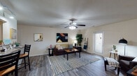 Located at 2201 Greenville Blvd in Greenville, NC, this single-floor unit offers a well-organized layout designed for comfortable everyday living. The living room serves as the centerpiece of the space, featuring durable hardwood-style flooring, a ceiling fan with integrated lighting, and a glass-paned exterior door that invites natural light and provides outdoor access. The room offers ample space for both lounging and entertainment setups.

The kitchen is efficiently designed with light wood cabinetry, dark laminate countertops, and a double-basin stainless steel sink. A pass-through window connects the kitchen directly to the living area, enhancing the open feel of the space. The kitchen also includes a full electric range with an over-the-range microwave, providing all essential cooking amenities.

The bedroom is a comfortable retreat with a window overlooking the outdoors, ceiling fan, and thoughtfully integrated built-in shelving and a dedicated study desk area. A walk-in closet offers generous storage. The unit includes two bathrooms — one full bath with a tub/shower combination adjacent to the bedroom, and a second bathroom with a single vanity and large mirror. Throughout, neutral wall tones and hardwood-style flooring create a cohesive and practical living environment.