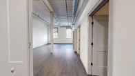Located at 330 Main St in Utica, NY, this thoughtfully designed 2-bedroom, 2-bathroom residence showcases a compelling blend of industrial heritage and modern upgrades. The open living area impresses with soaring ceilings, exposed ductwork, whitewashed wood ceiling planks, and structural columns that nod to the building's historic character, all grounded by durable dark hardwood-style flooring throughout. Natural light filters in through large double-hung windows, brightening the expansive main living space. The kitchen is outfitted with crisp white shaker cabinetry, a subway tile backsplash, light stone countertops, and a full suite of stainless steel appliances including a French door refrigerator, range, microwave, and dishwasher. Both bathrooms feature light large-format tile flooring and dark vanity cabinetry with clean white countertops. One bathroom includes an exposed painted brick accent wall, adding a distinctive industrial touch. The generously sized primary bedroom includes a walk-in closet with extensive built-in shelving and hanging systems, while the second bedroom features a classic bi-fold double closet. Two additional closets provide ample storage throughout the residence. The layout flows efficiently, connecting all rooms with a cohesive, modern aesthetic.