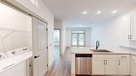 Located at 6170 Kitt Ln NW in Huntsville, Alabama, this well-designed one-bedroom, one-bathroom unit offers a thoughtfully organized single-floor layout that maximizes every square foot. The open-concept kitchen and living area serves as the heart of the home, featuring white shaker cabinetry with matte black hardware, granite countertops, a peninsula with an undermount sink, and a full suite of stainless steel appliances including a refrigerator, electric range, microwave, and dishwasher. Light wood-style plank flooring extends throughout the entire unit, creating a cohesive and clean aesthetic. The living area is bright and airy, anchored by a set of French doors that invite natural light and provide access to the outdoors. The bedroom is a comfortable, private retreat equipped with a ceiling fan and a window with natural light. The bathroom is generously appointed with a granite-topped double vanity, matte black fixtures, built-in open shelving, and a separate walk-in shower with a glass door. A dedicated closet provides additional storage. Crisp white walls and recessed lighting throughout lend a modern, fresh feel to this move-in-ready Huntsville residence.