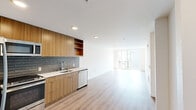 Located at 4725 38th Ave S in Seattle's vibrant 98118 corridor, this 2-bedroom, 1-bathroom unit offers a thoughtfully designed, modern interior with a clean, contemporary aesthetic throughout. Light wood-tone flooring flows seamlessly across the entire space, lending warmth and visual continuity to every room.

The open-concept kitchen and living area forms the heart of the unit. The kitchen is outfitted with flat-front wood-grain cabinetry, open shelving, a sleek white countertop, and a blue-gray subway tile backsplash. Stainless steel appliances — including a French door refrigerator, gas range, built-in microwave, and dishwasher — complete this well-equipped space. The living area extends toward large sliding glass doors that open to a private balcony, allowing generous natural light to pour in and offering views of the surrounding neighborhood.

Both bedrooms are bright and cleanly finished with white walls and light flooring. The primary bedroom features floor-to-ceiling sliding glass doors leading to a balcony, and includes a walk-in closet with built-in shelving. The bathroom is finished with a warm wood vanity, a white undermount sink with a backlit mirror, and a full soaking tub with vertically tiled subway surround. A hallway connects all rooms with efficient flow throughout this well-appointed Seattle residence.