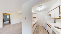 Located at 5501 Cambridge Club Circle in Ann Arbor, Michigan, this two-bedroom, one-bathroom residence offers a practical and well-organized single-floor layout. The open-concept kitchen and living room area forms the heart of the home, where the kitchen features white cabinetry with warm wood-tone trim accents, a peninsula countertop that opens to the living space, white appliances including a refrigerator and range, and light hardwood-style flooring. Ample upper and lower cabinet storage ensures functional use of the space.

The living room is bright and airy, finished with neutral carpet and anchored by a large sliding glass door that frames outdoor greenery and fills the room with natural light. Both bedrooms continue the carpeted flooring and clean white walls, with windows dressed in vertical blinds providing additional natural light. The primary bedroom includes a mirrored sliding-door closet, offering generous storage.

The full bathroom is finished with hardwood-style flooring, a wide vanity with a white countertop and sink, a large mirror, and a shower-tub combination. A dedicated utility room and hallway round out the layout. Throughout, the space maintains a clean, neutral palette that offers a move-in-ready, functional living environment.
