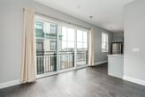 This 1-bedroom, 1-bathroom unit delivers a clean, modern aesthetic with well-chosen finishes throughout. The kitchen is a standout feature, showcasing gray shaker-style cabinetry, gleaming white quartz countertops, and a classic subway tile backsplash. Stainless steel appliances — including a refrigerator, electric range, built-in microwave, and dishwasher — complete the space, while a peninsula with additional storage and counter space adds both functionality and a natural division within the open layout. Dark hardwood-style flooring runs through the kitchen and main living area, lending warmth and contrast to the bright, neutral walls. Natural light filters in through multiple windows fitted with blinds, keeping the space feeling airy and open. The bedroom features plush carpet underfoot and a spacious walk-in closet with built-in wire shelving, accessed through a sleek three-panel sliding door. The bathroom is finished with elegant marble-look tile surrounding the tub and shower, complemented by a quartz vanity and coordinating gray cabinetry. A stacked washer and dryer unit, visible in the floor plan, adds everyday convenience. The overall design is cohesive and contemporary, making efficient and stylish use of the available space.