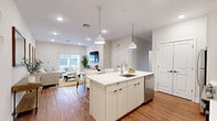 Located at 106 Stonebridge Ct in Cheshire, CT, this well-designed 2-bedroom, 1-bathroom residence offers a thoughtfully planned single-level layout with a clean, contemporary aesthetic. Warm hardwood flooring flows throughout the entire home, complementing the bright, neutral color palette that creates a cohesive and inviting atmosphere.

The open-concept kitchen, dining, and living area forms the heart of the home. The kitchen features white cabinetry extending to the ceiling, stainless steel appliances, and a generous center island with a white quartz countertop, undermount sink, and pendant lighting — ideal for both meal prep and casual dining. The adjoining dining area accommodates a full dining set, while the living room benefits from a sliding glass door that opens to an outdoor patio, filling the space with natural light.

Both bedrooms are comfortably sized, with the primary bedroom offering multiple windows and ample natural light. Two closets provide practical storage throughout the home. The full bathroom is finished with a floating vanity, large mirror, and a shower-tub combo, while a separate room features a walk-in shower and built-in shelving, reflecting a clean, modern design sensibility throughout.