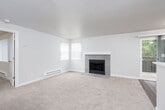This single-floor residence offers a well-organized layout that balances comfort and functionality across its living spaces. The spacious living room serves as the heart of the unit, highlighted by a tile-surround fireplace that anchors the room as a central focal point. Neutral-toned carpet covers the generous floor area, while multiple windows allow natural light to filter in. A sliding glass door provides direct access to a private balcony, extending the living space outdoors. Baseboard heating units are present along the walls, ensuring year-round comfort.

The galley-style kitchen is thoughtfully designed with gray shaker cabinetry, white quartz countertops, and wood-look vinyl plank flooring. White appliances, including a range and refrigerator, complement the clean aesthetic, while a single-basin sink with a modern faucet sits along the countertop peninsula that opens toward the main living area.

The bathroom is outfitted with updated finishes, including a gray vanity with brushed nickel hardware, a white quartz countertop, an undermount sink, and a large mirror with a medicine cabinet. A full tub-shower combination and wood-look flooring complete the space, creating a clean, contemporary feel throughout.